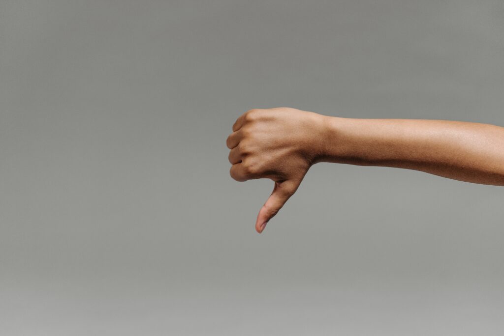 Image of someone pointing their thumb down.