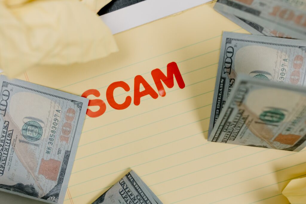 Image showing a note saying "Scam" with money on top of it.