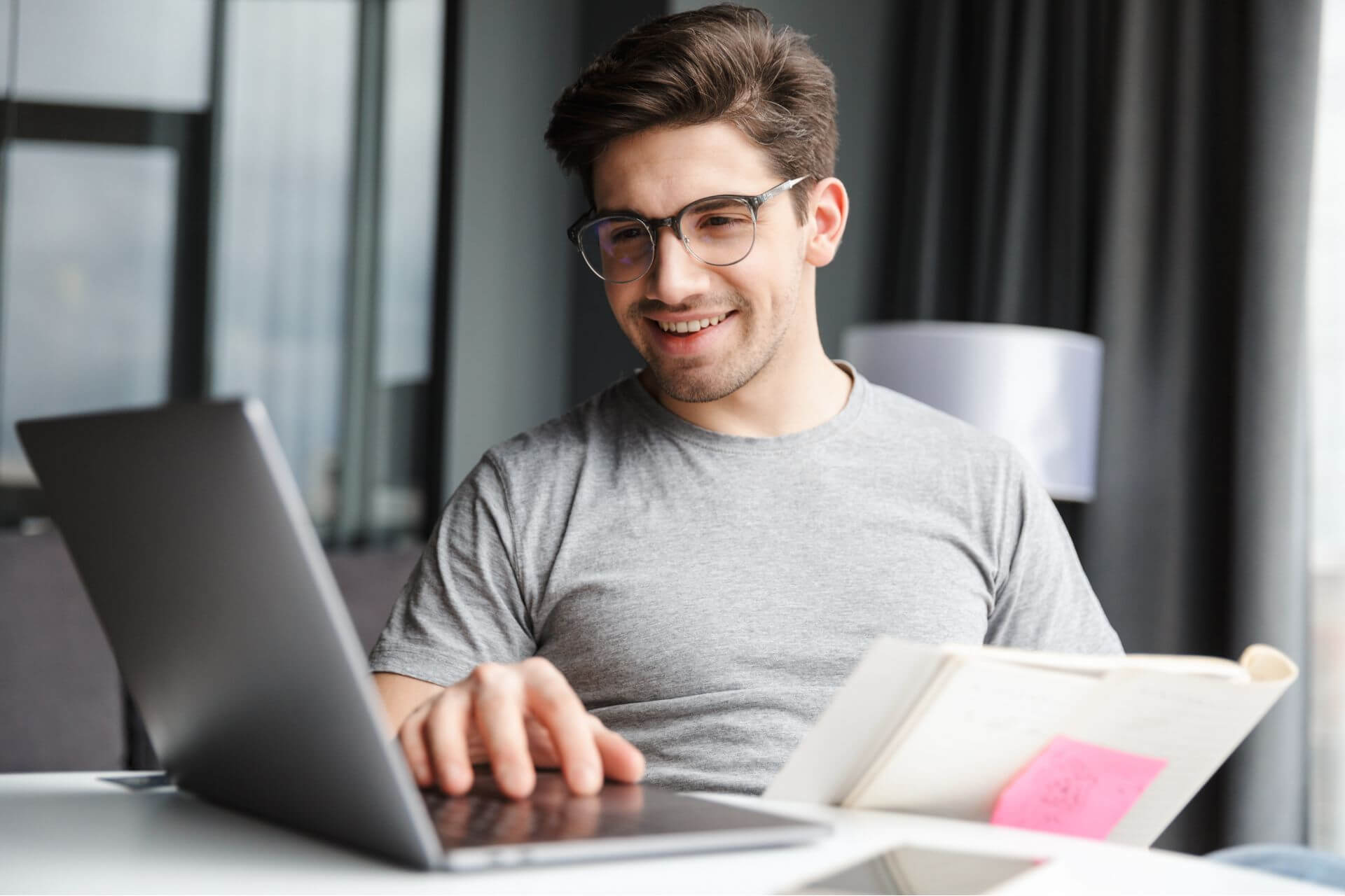 A man in glasses working on a laptop, engrossed in his tasks.
